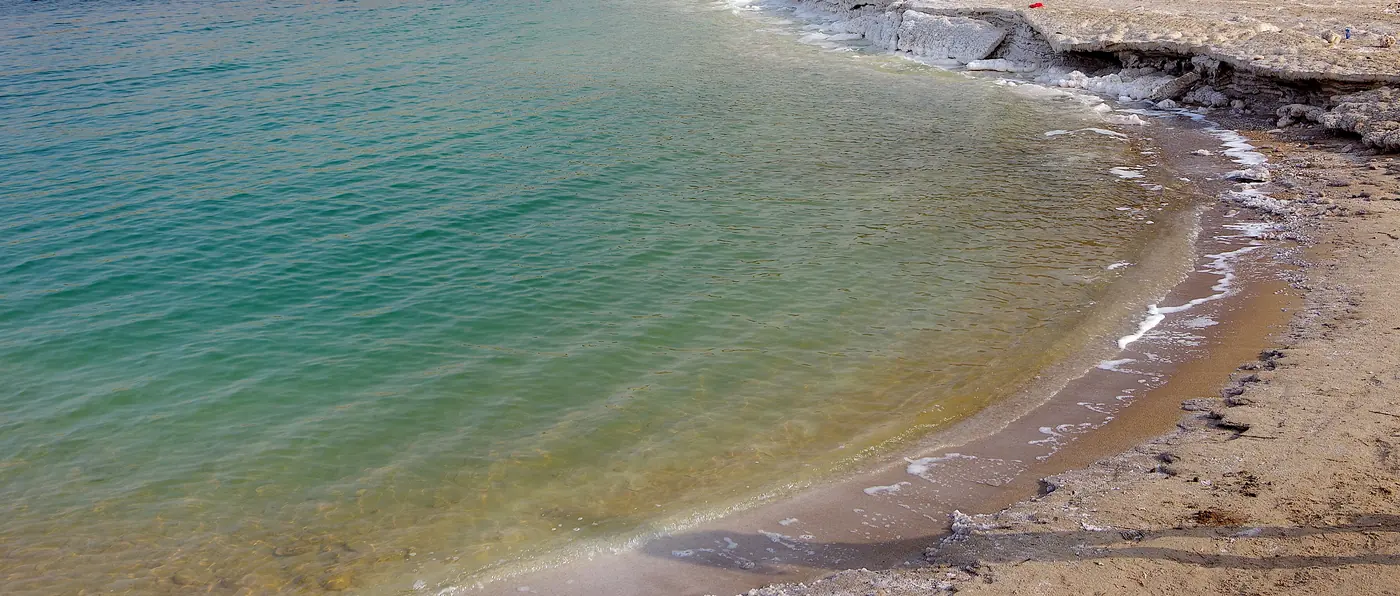 Turquoise water and white salt along the shore of the Dead Sea in Jordan