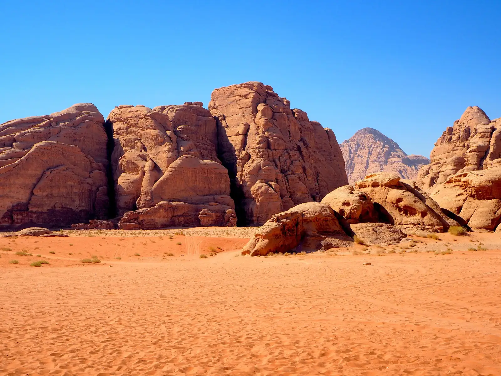 Sandstone cliffs rising above red sand in the Wadi Rum desert in southern Jordan